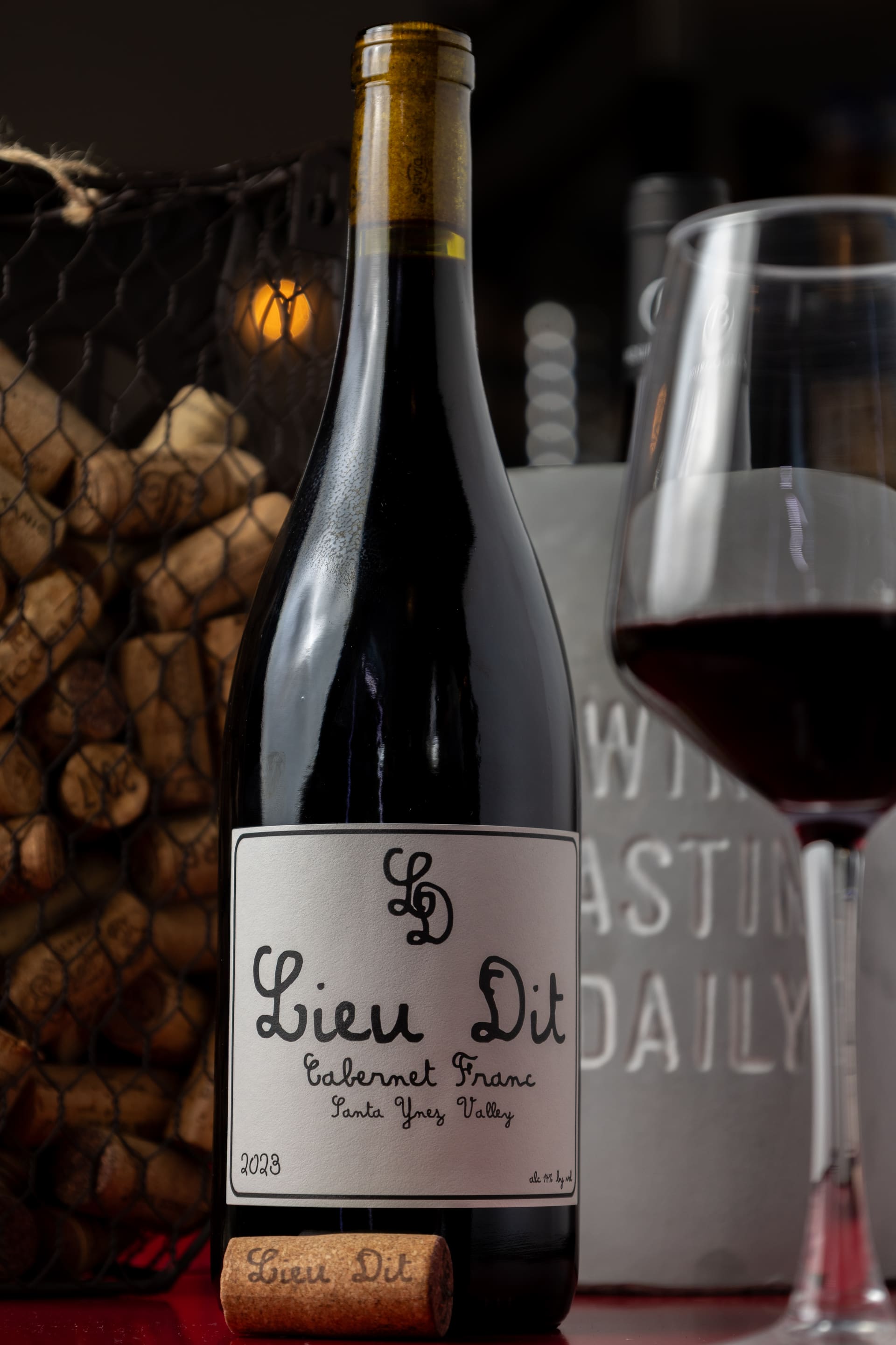 Botella de vino tinto junto a una copa servida.
