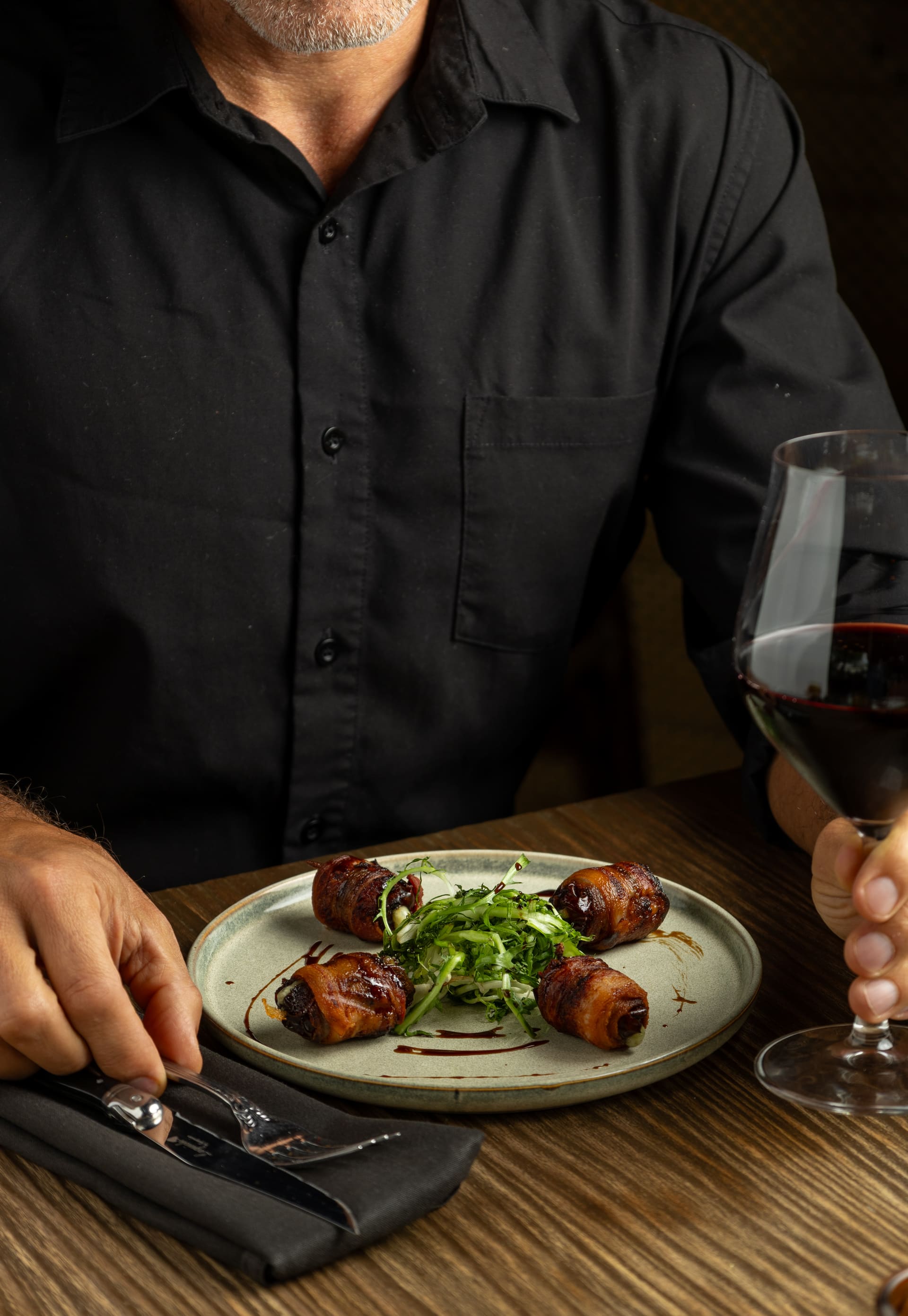 Comensal con copa de vino frente a un plato de entrada.