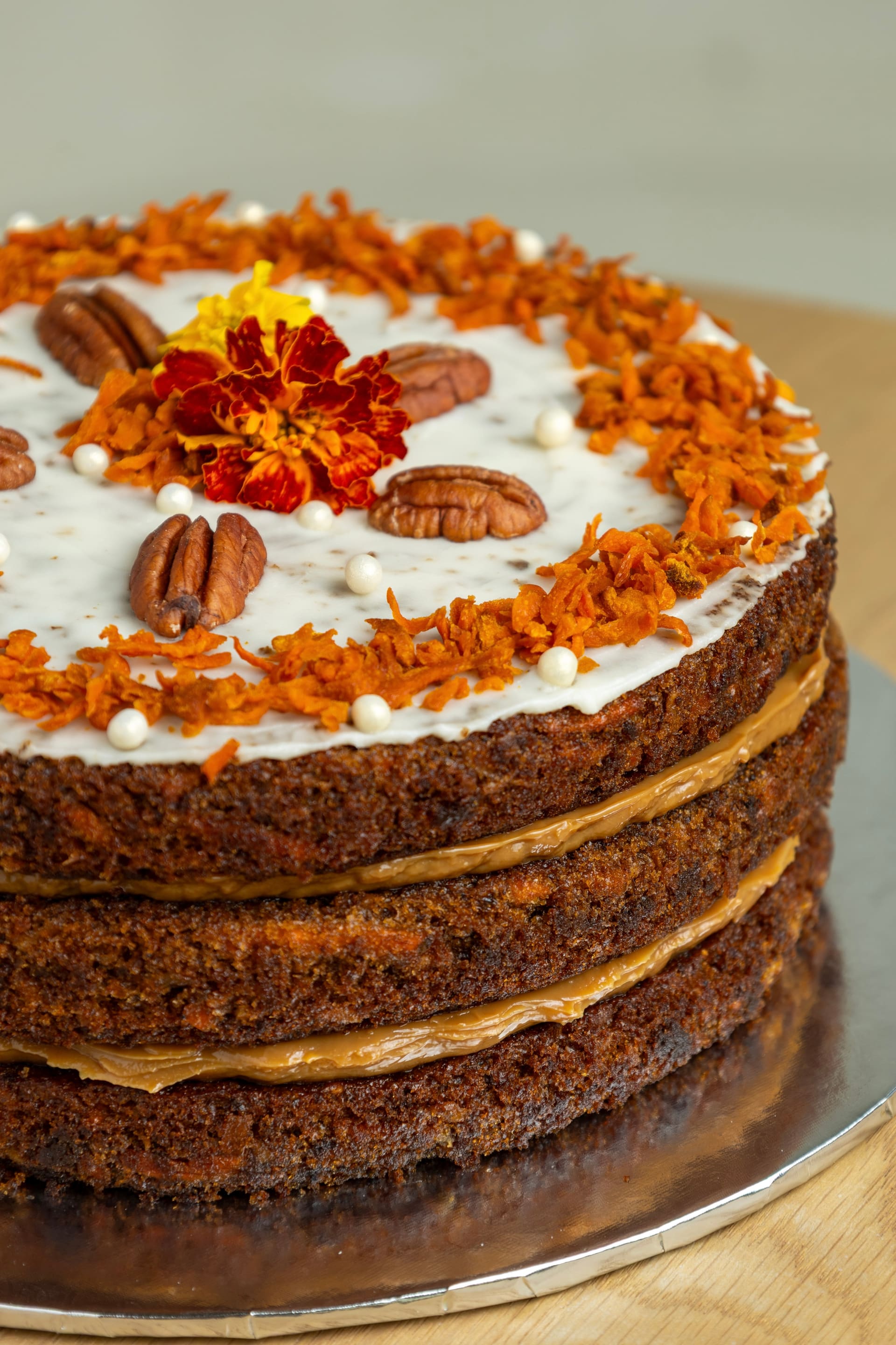 Torta de zanahoria de varios pisos decorada con nueces y flores.