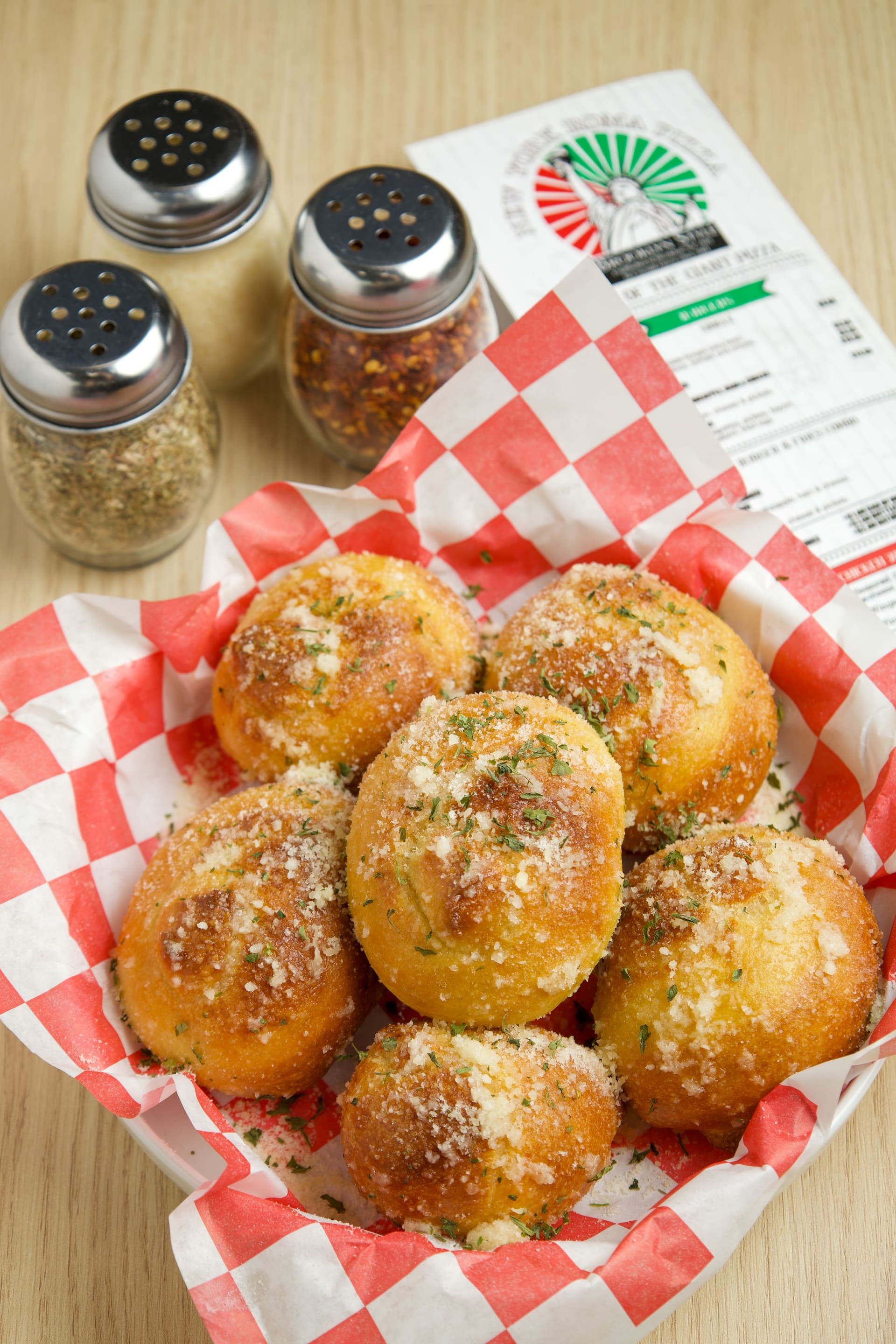 Canasta de pan de ajo con queso sobre papel a cuadros.